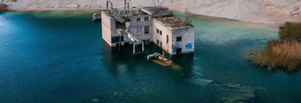 Abandoned concrete building in bright turquoise quarry lake
