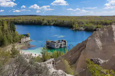 Abandoned multi-story building in turquoise quarry lake