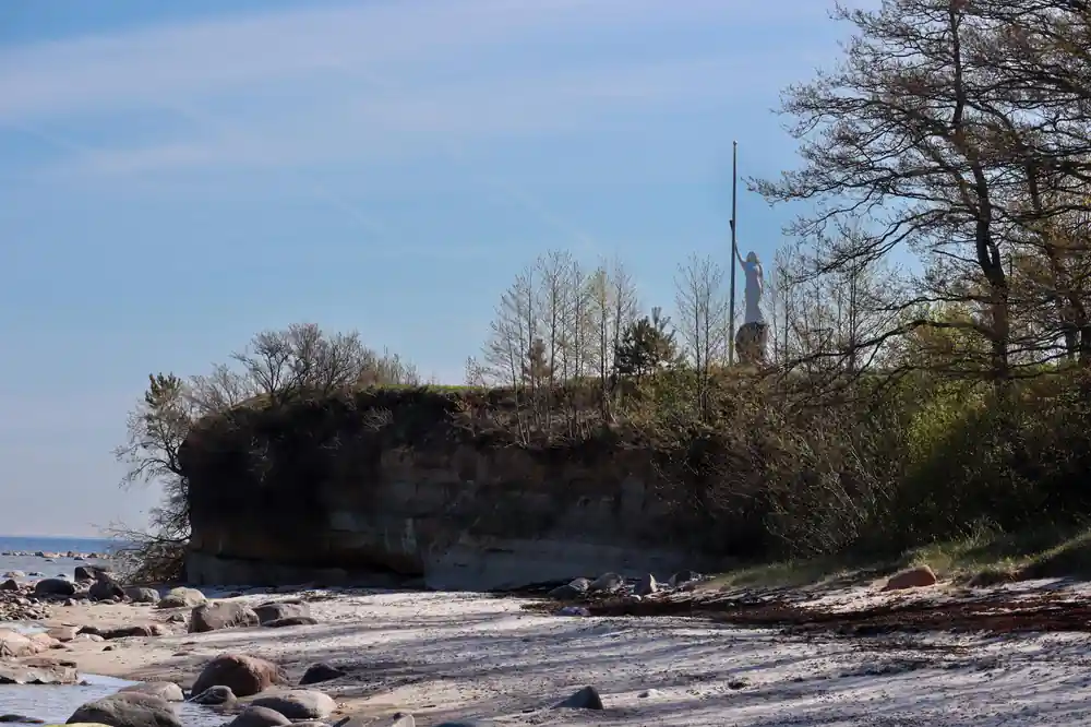 Concrete bunker on beach with trees above cliff