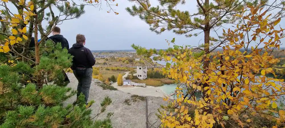 Person hiking through autumn woodland toward distant building