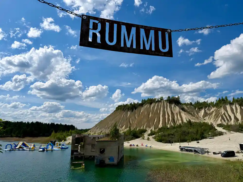 Quarry lake with RUMMU sign and sandy cliff