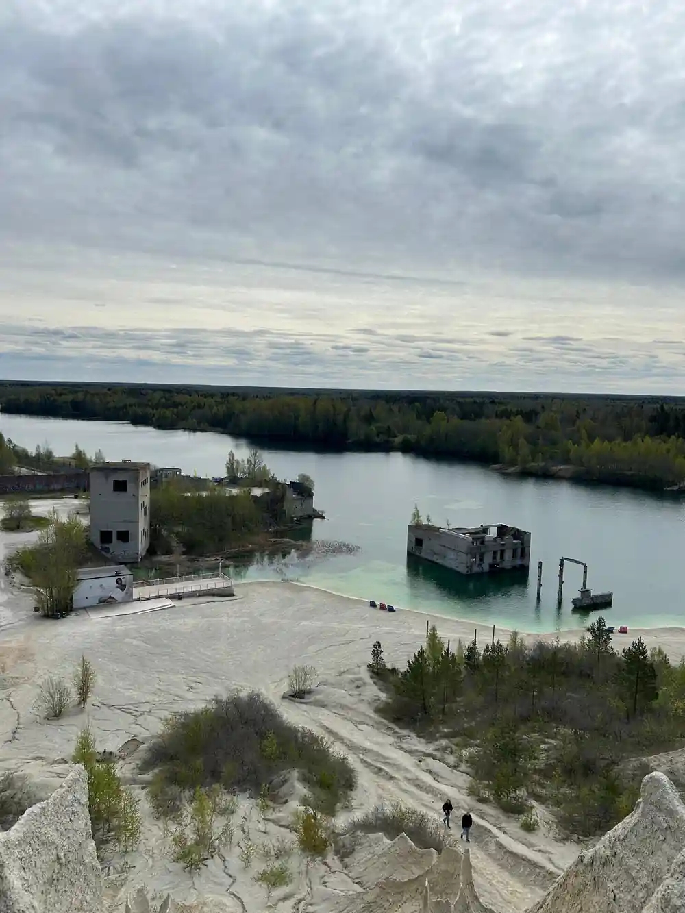 Quarry pit with turquoise water and industrial building