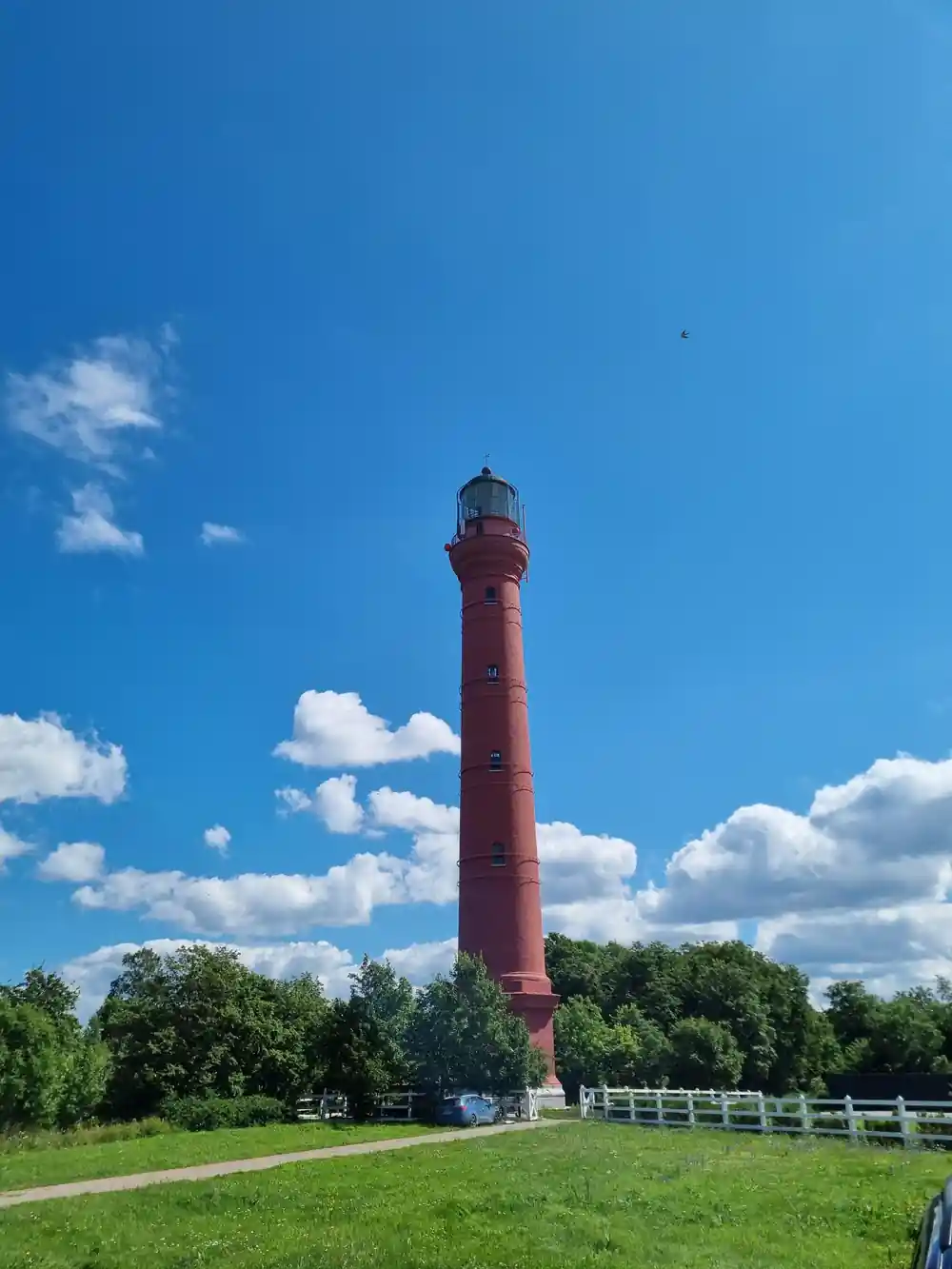 Red brick lighthouse tower in flat pastoral landscape
