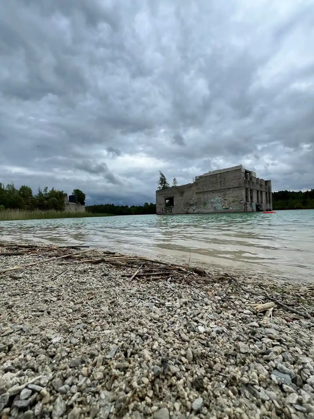 Ruined stone building in water surrounded by cloudy sky
