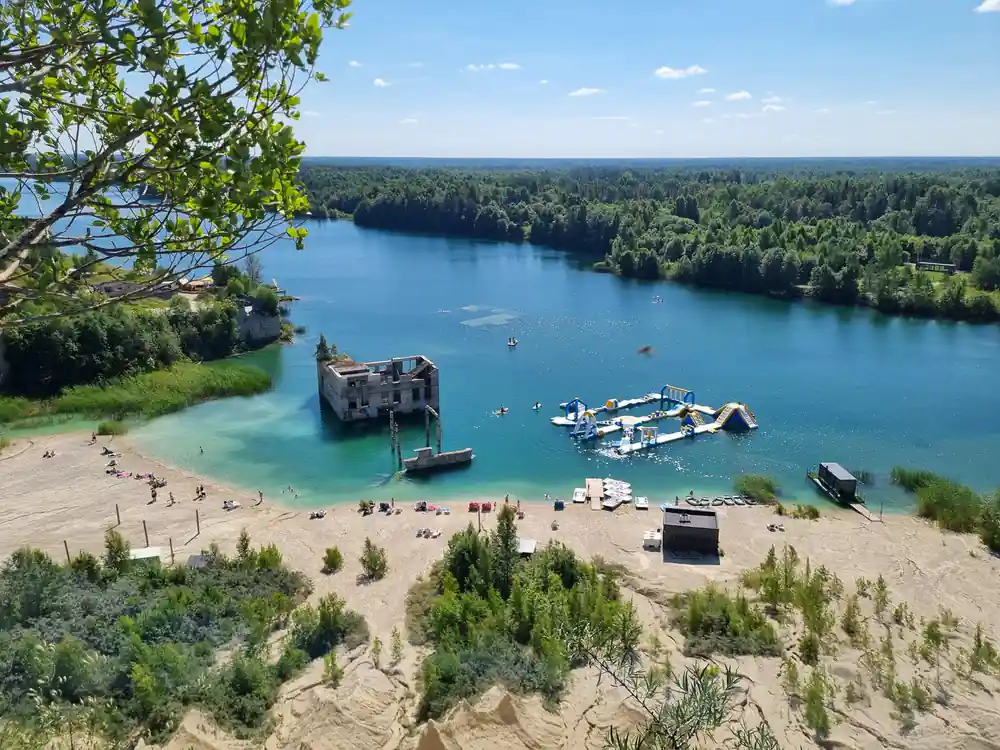 Sandy beach with ruined building and boats in turquoise lake