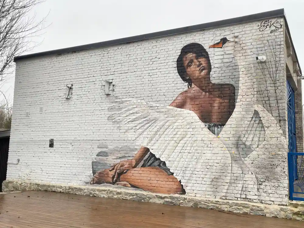 Street art mural of person with white feathered wings