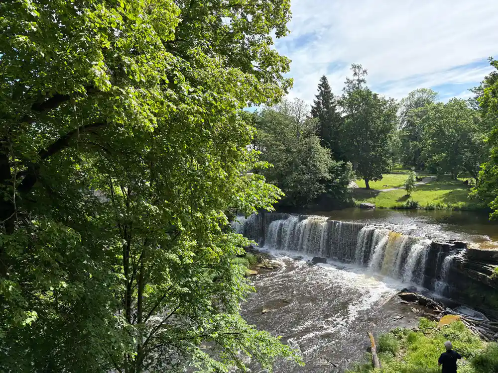 Waterfall flowing through green river valley landscape